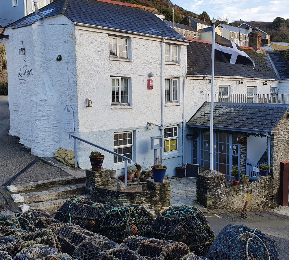 The exterior of the Lugger Hotel, Portloe with Cornish flag and Lobster pots