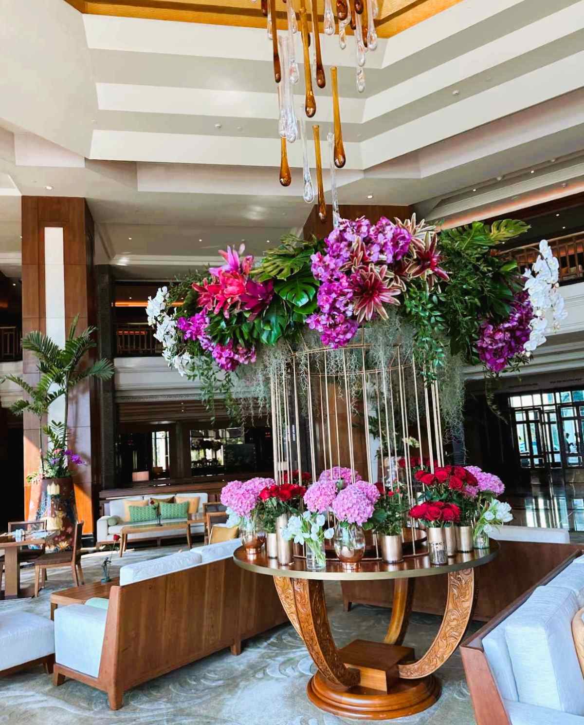 The Peninsula lobby bar overlooks the garden and the Chao Phraya river and has a water drop chandelier and is festooned with flowers