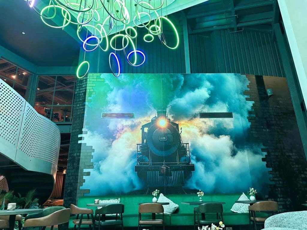 The entrance lobby at Aloft By Marriott Manchester has a large mural of a steam train and an eye-catching light installation